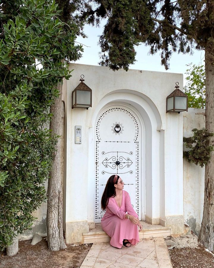 Laura in a pink dress sitting on steps in front of building in Tunisia